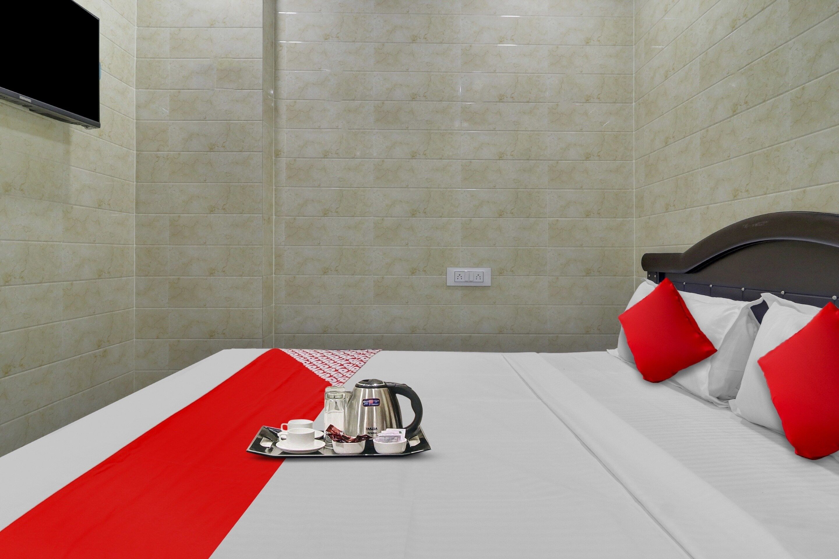 Una habitación de hotel con una cama, una bandeja con tetera, una taza y un tazón pequeño.