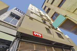 Un edificio de varios pisos con un cartel que dice 'OYO ROOMS', indicando un hotel o alojamiento.