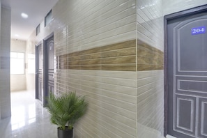 Un pasillo con pared de azulejos, una planta en maceta y una puerta con el número 204.