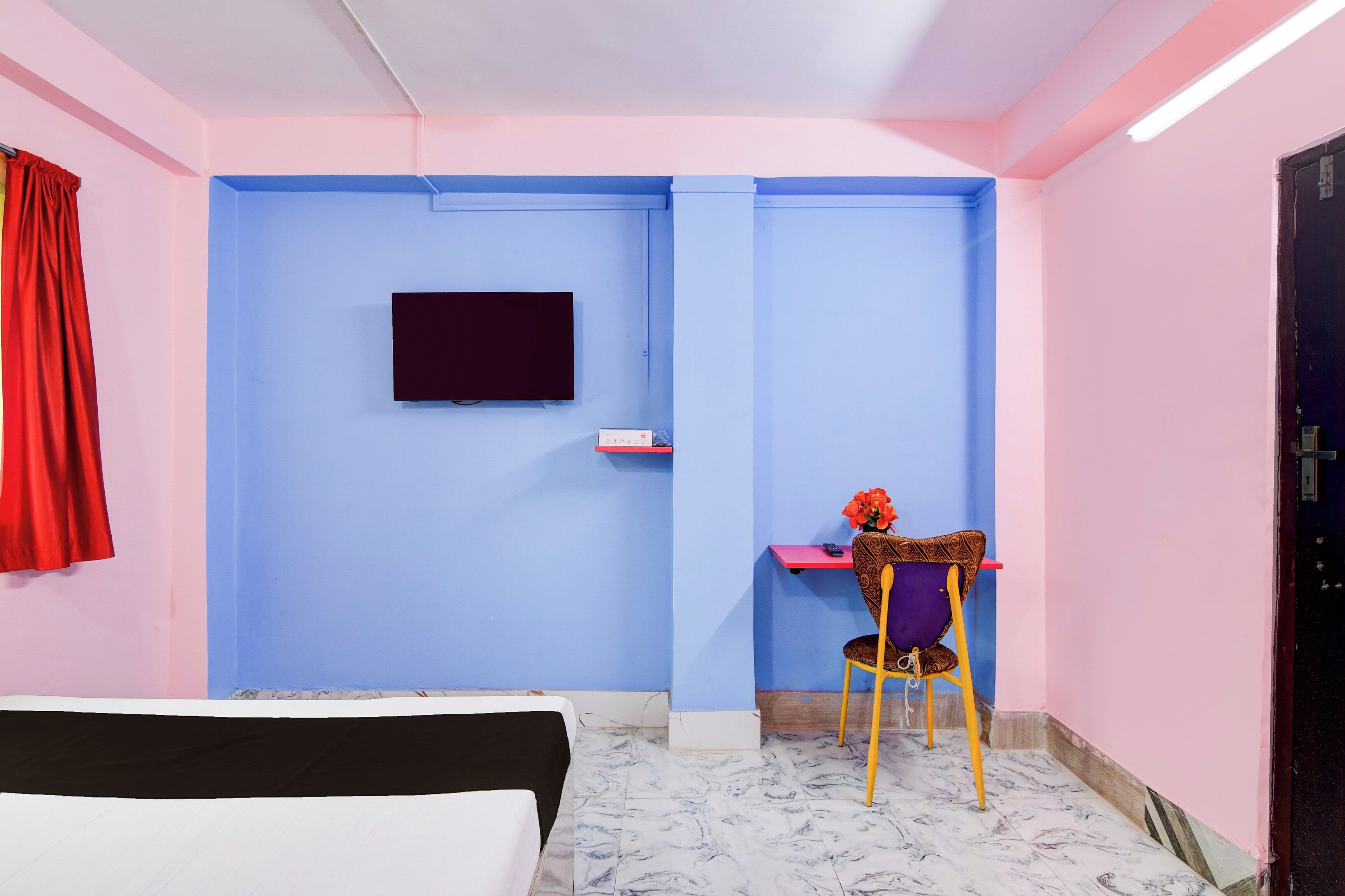 Una habitación con una cama, un escritorio, una silla, un televisor y una puerta.