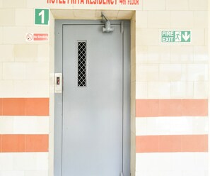 A hotel entrance with a fire exit sign, a no smoking sign, and a door marked with the number 1. - Deluxe Vaishnavi Residency (Hyderabad)
