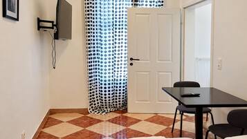 A room with a bed, a desk, a chair, a television, and a door.