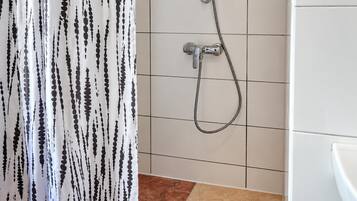 A bathroom with a shower, tiled walls, and a patterned curtain.