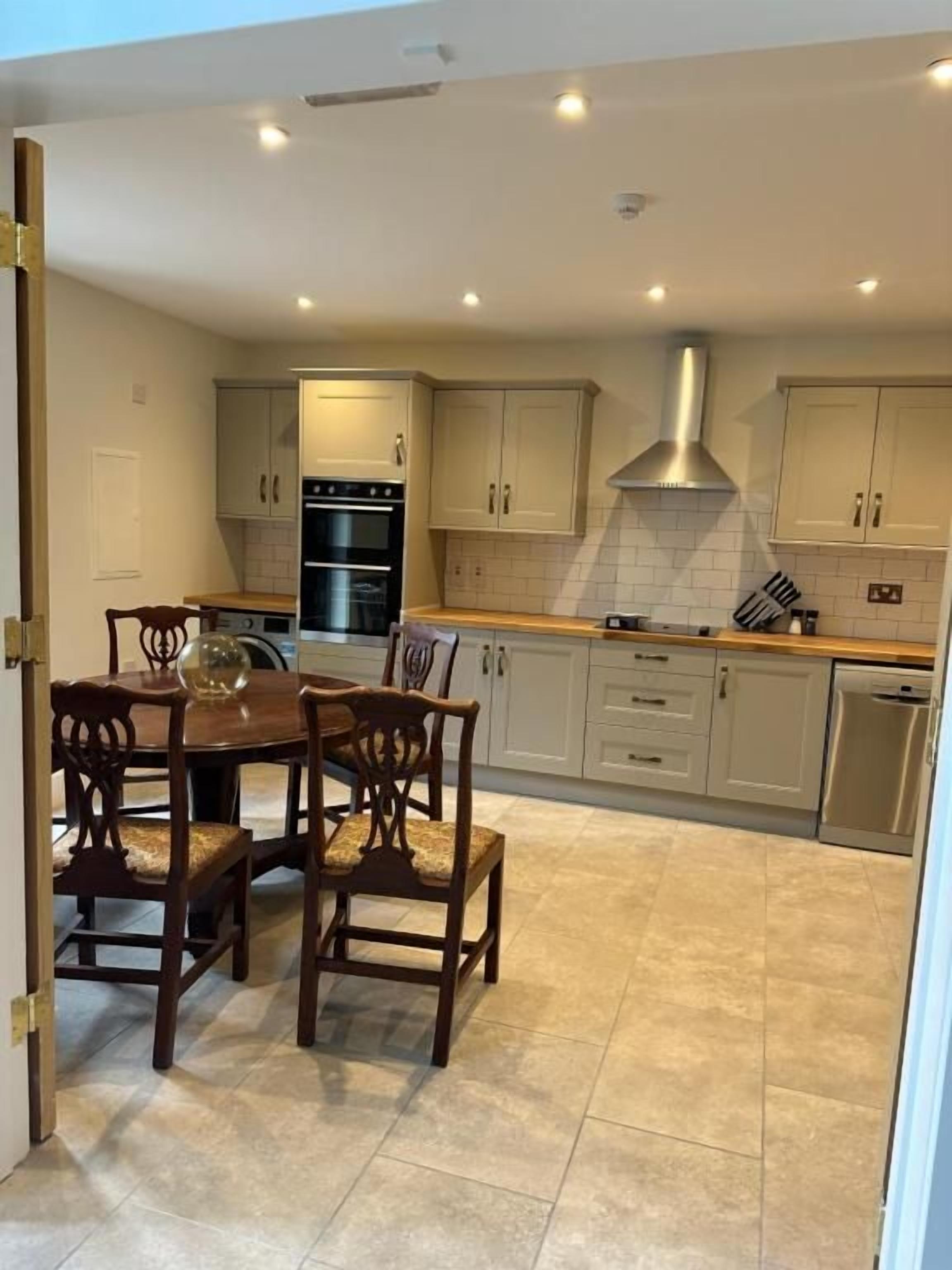 A kitchen with a dining table and chairs, cabinets, an oven, and a dishwasher.