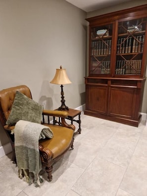 A room with a leather armchair, a small table with a lamp, and a wooden bookcase. - The Coach House  (Mountmellick)