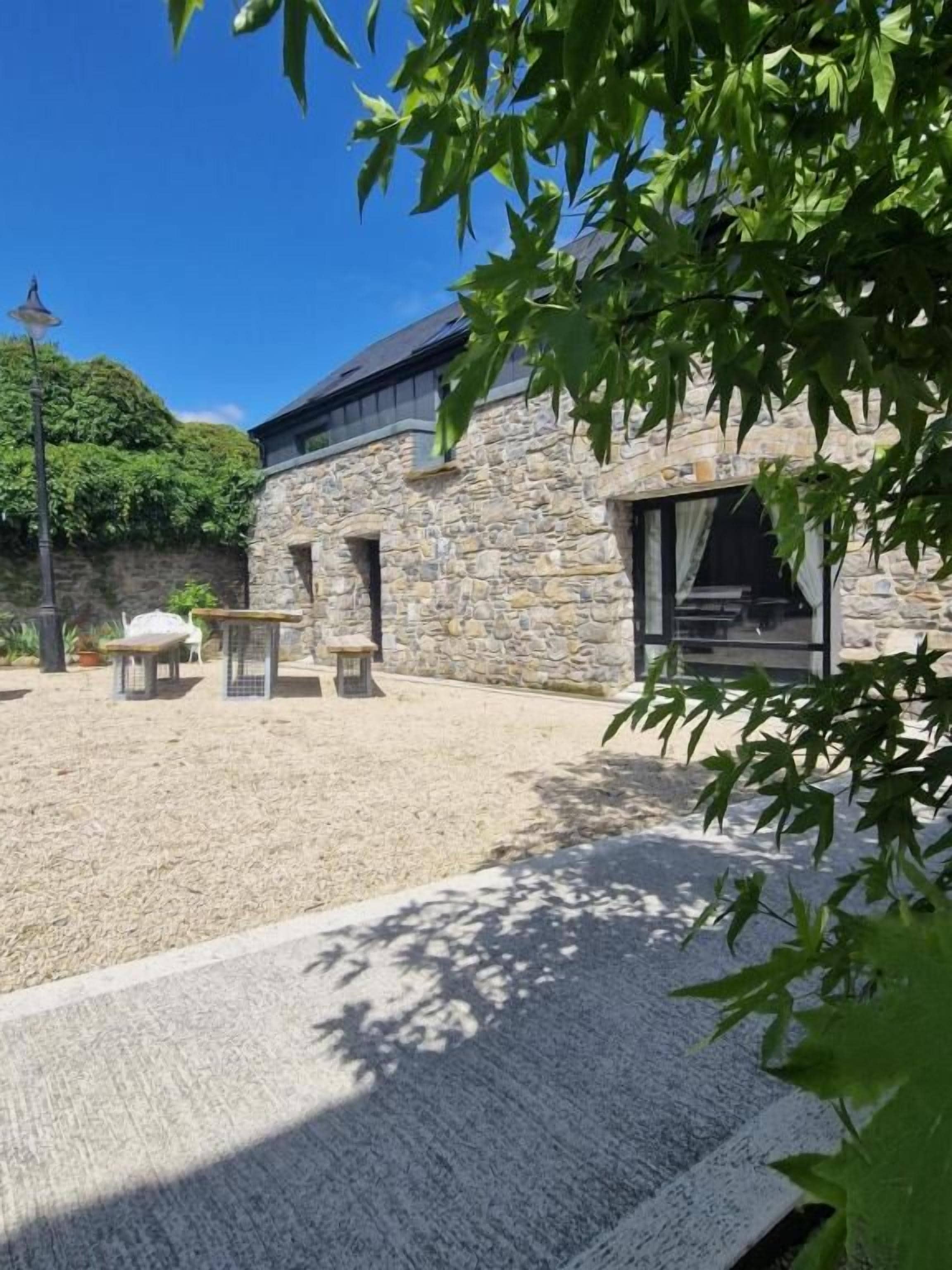 A stone building with a covered patio area, outdoor seating, and a lamp post.