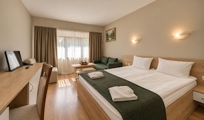A hotel room with a bed, desk, chair, and a small table with a plant. - Hotel Forestia (Borovets)