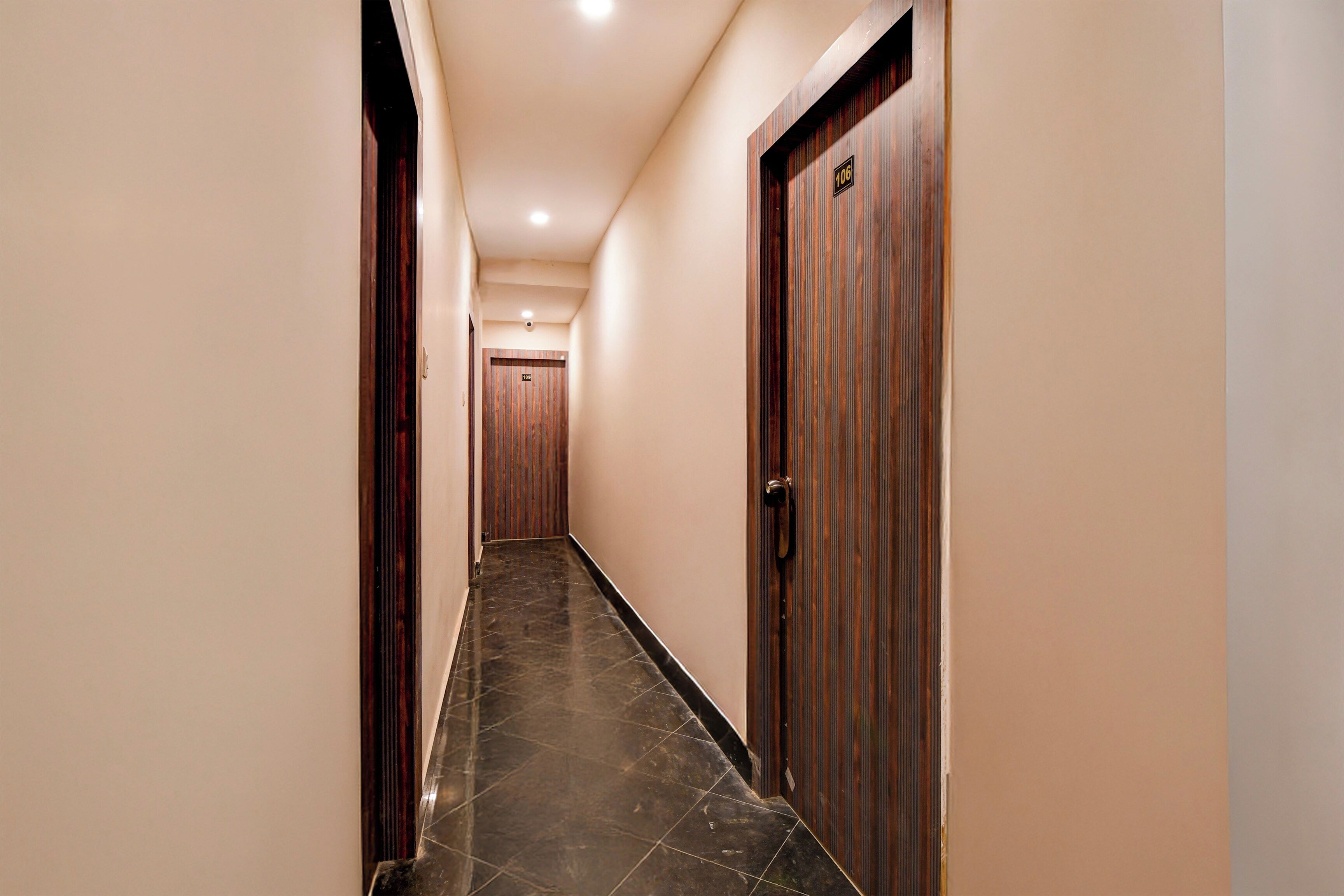 A hallway with a wooden door on the right, a door at the end, and a tiled floor.