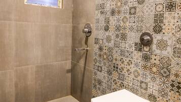 Un baño con ducha, inodoro y ventana.