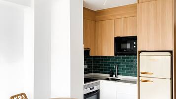 Una cocina moderna con armarios de madera, un refrigerador blanco y un comedor con sillas de mimbre y una mesa redonda.