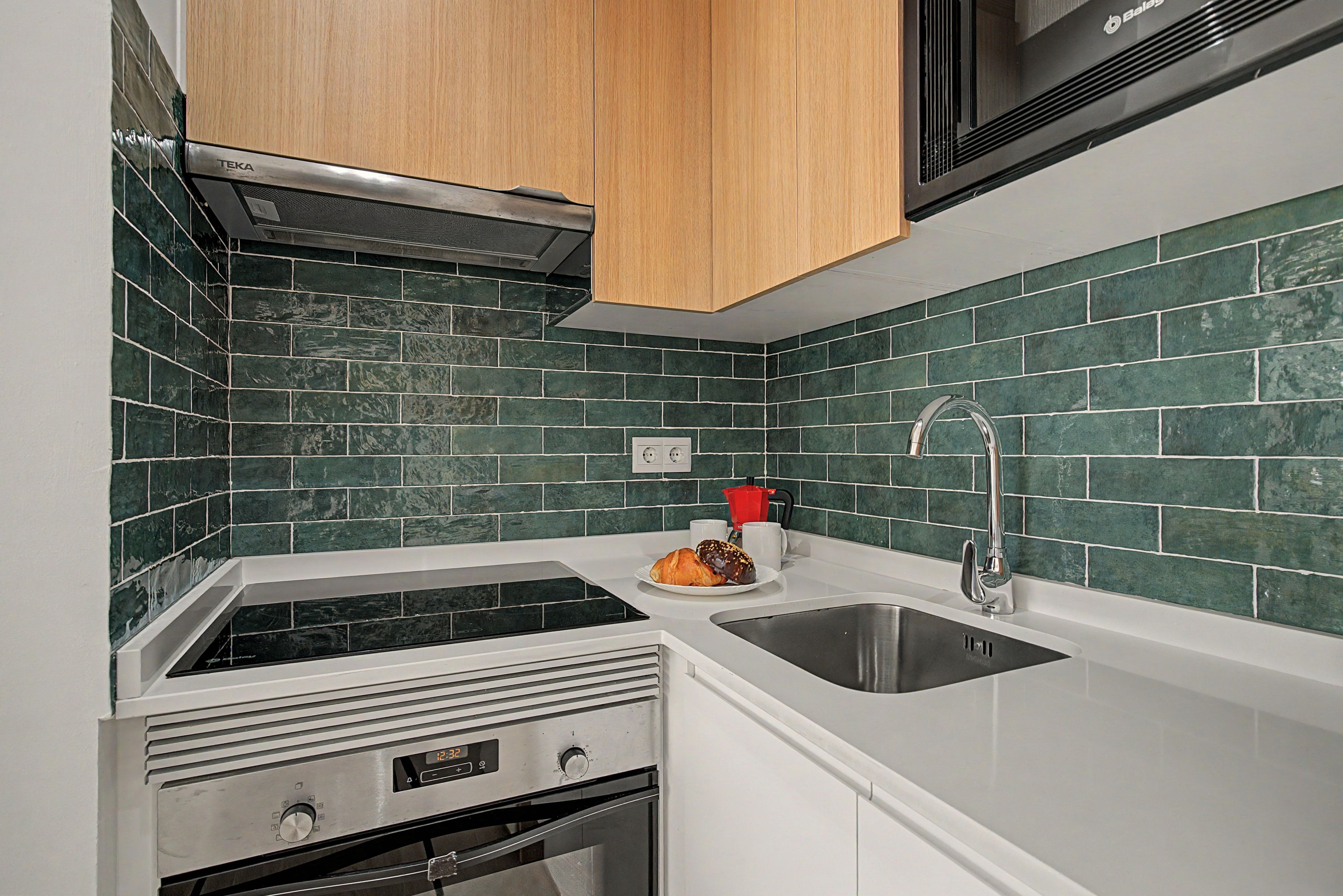 Una cocina con estufa integrada, un lavamanos y un microondas.