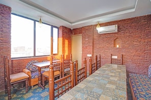 Una habitación con pared de ladrillo, un ventanal grande, una mesa de madera y suelo con diseño.