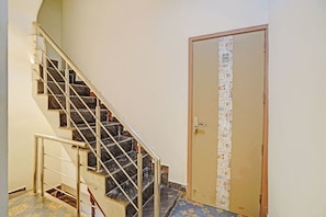 Una escalera con barandillas de metal que conduce a una puerta con un cortinero estampado.