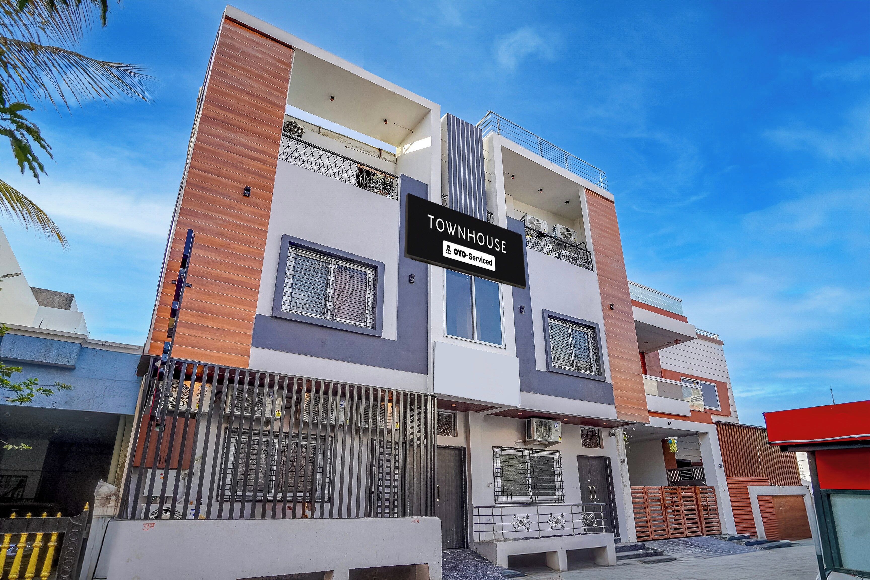 A modern two-story building with a sign indicating it is a 'TOWNHOUSE' and 'OYO-Serviced'.