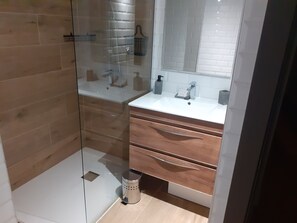 A modern bathroom with a glass shower enclosure, a white sink, wooden vanity, and a mirror above the sink. - New Listing (Port-Vendres)