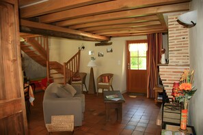 A cozy living room with a sofa, a small table, a lamp, and a fireplace. - Holiday Home 'Les Basroches' with Private Terrace, Private Garden and Wi-Fi (Mardié)