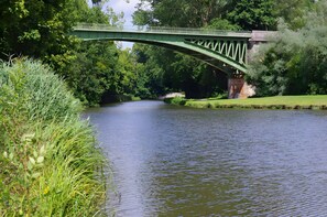 A green metal bridge over a calm river, surrounded by lush greenery and trees. - Holiday Home 'Les Basroches' with Private Terrace, Private Garden and Wi-Fi (Mardié)