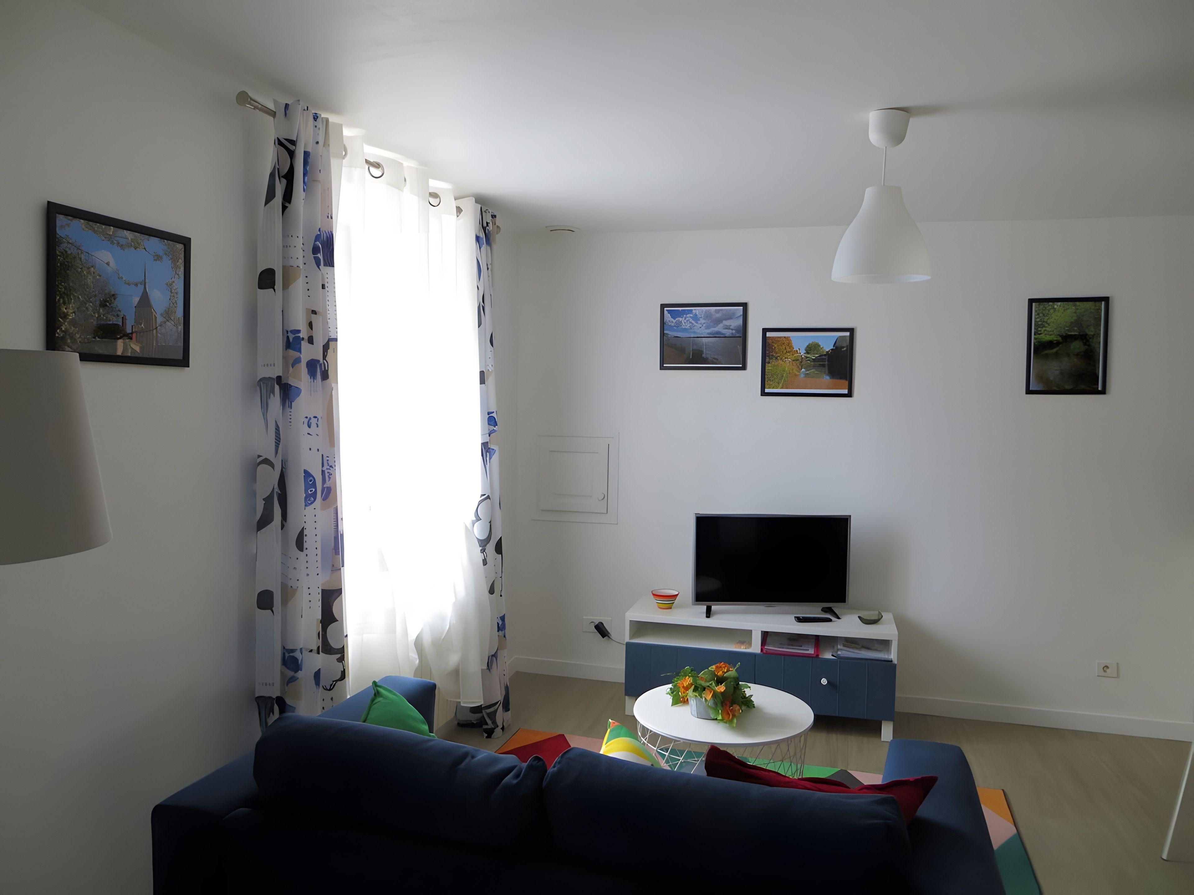 A living room with a sofa, a TV, and a small table with flowers.