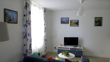 A living room with a sofa, a TV, and a small table with flowers.