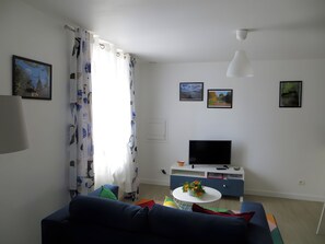 A living room with a sofa, a TV, and a small table with flowers.