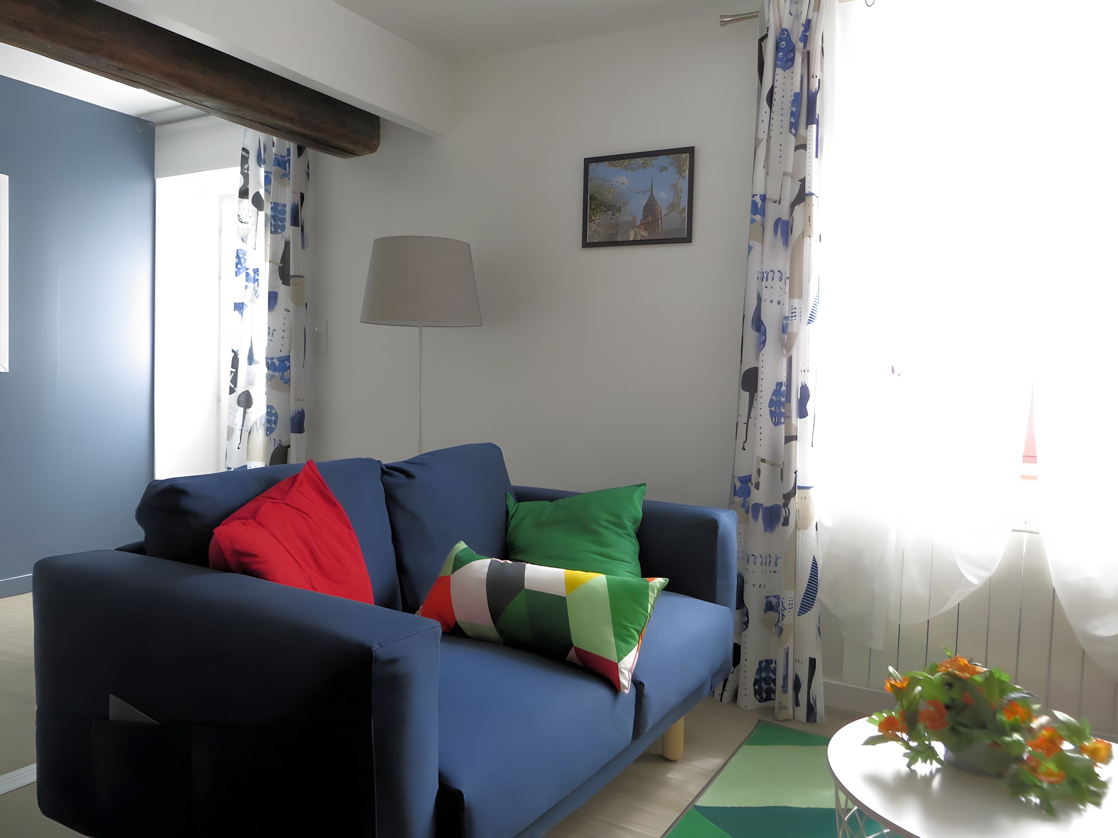 A living room with a blue sofa, a lamp, and a painting on the wall.