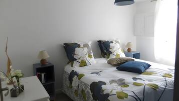 Quarto bem arrumado com cama, mesas de cabeceira e abajur.