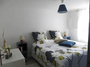 Quarto bem arrumado com cama, mesas de cabeceira e abajur.