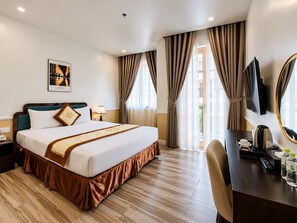 A hotel room with a large bed, a desk with a mirror, a TV, and a window with curtains. - MER HARRY HOTEL PHU QUOC (Phu Quoc)
