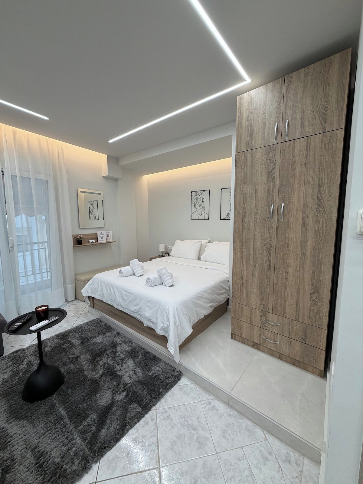 Une chambre à coucher moderne, avec un lit, des tables de chevet, une armoire et des œuvres d’art accrochées aux murs.