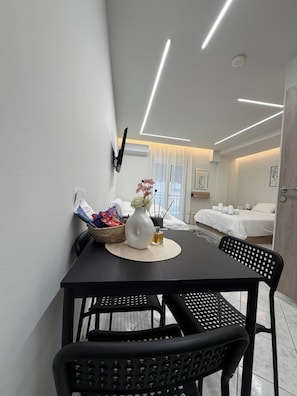 Une chambre d’hôtel moderne dotée d’un coin repas comprenant une table, des chaises et un vase avec des fleurs.