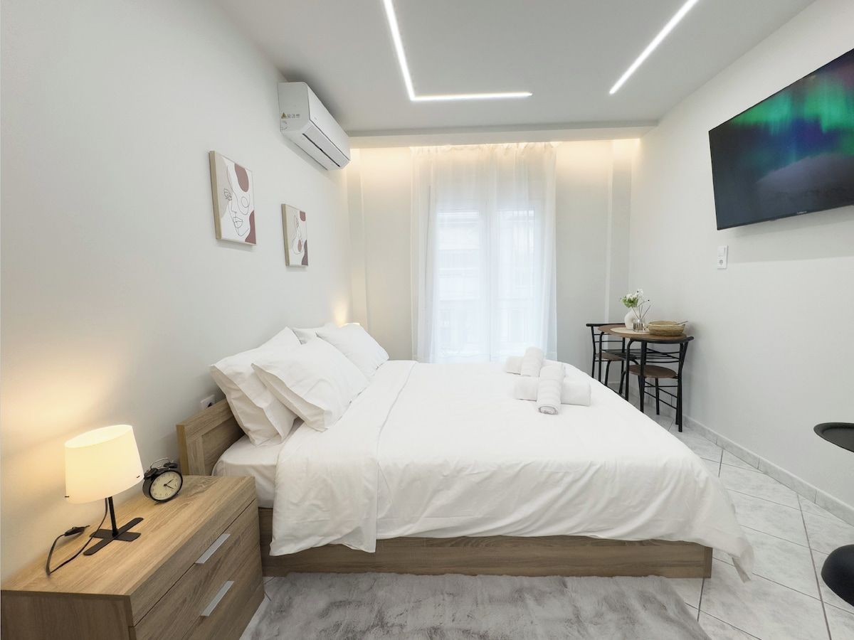 Ein modernes Schlafzimmer mit Bett, Nachttisch, Lampe und Fernseher an der Wand.
