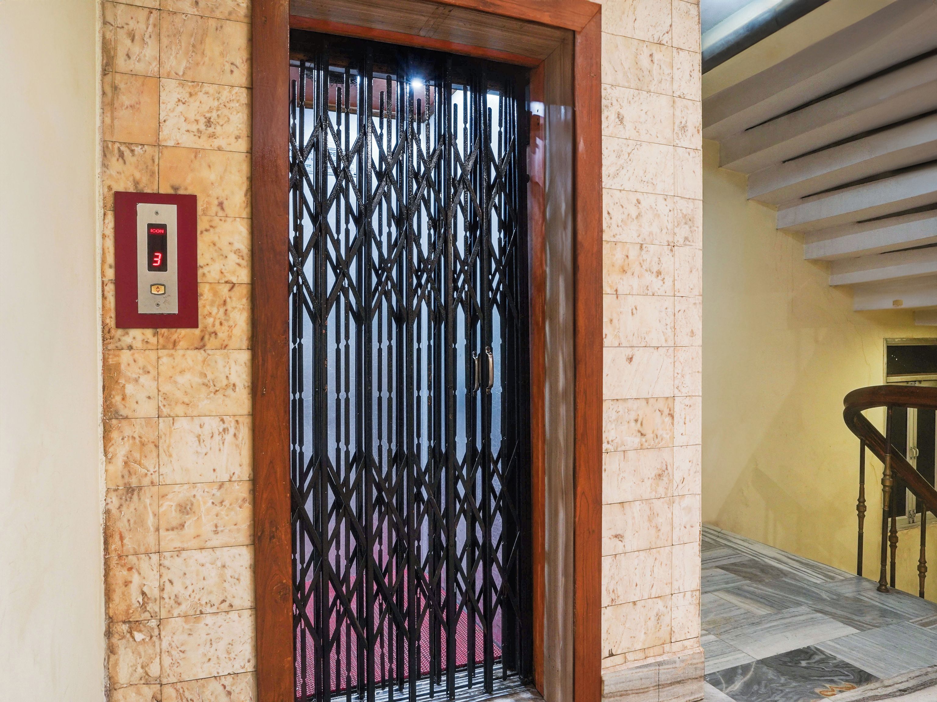 A hotel entrance with a metal gate, a digital elevator display, and a marble floor.