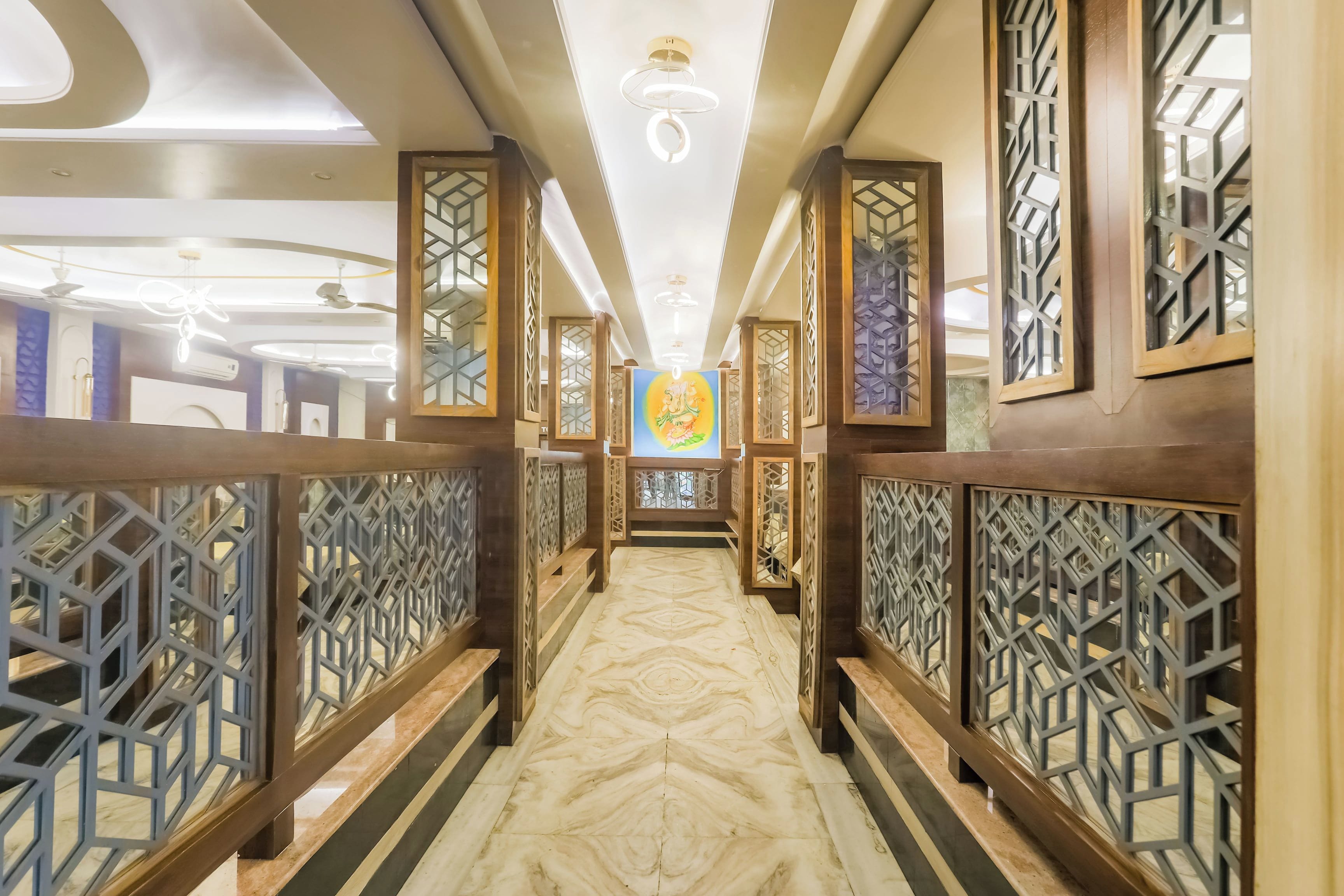 A corridor with patterned wooden railings, a marble floor, and a ceiling with recessed lighting.