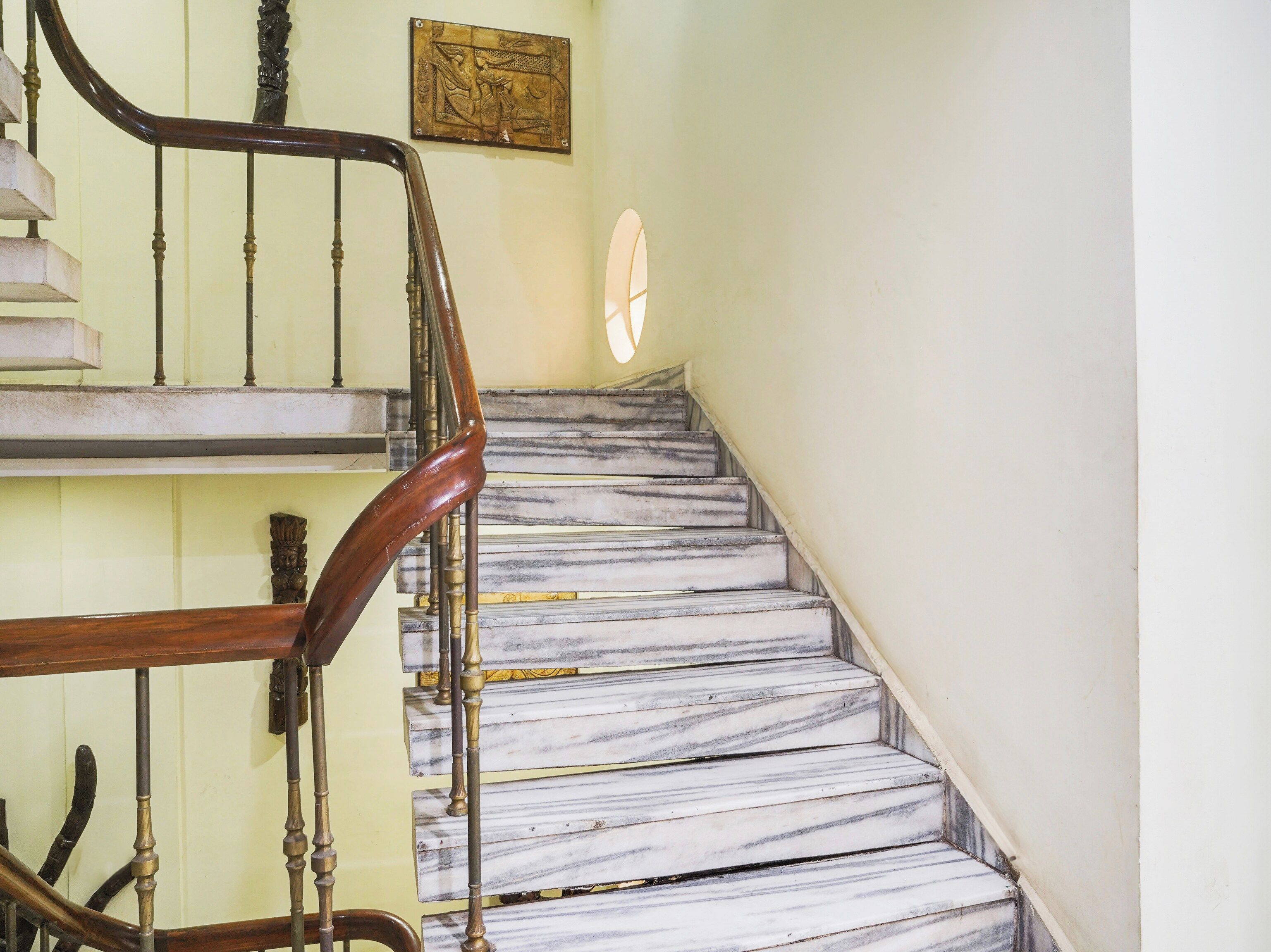 Una escalera de mármol con barandilla de madera y una obra de arte en la pared.