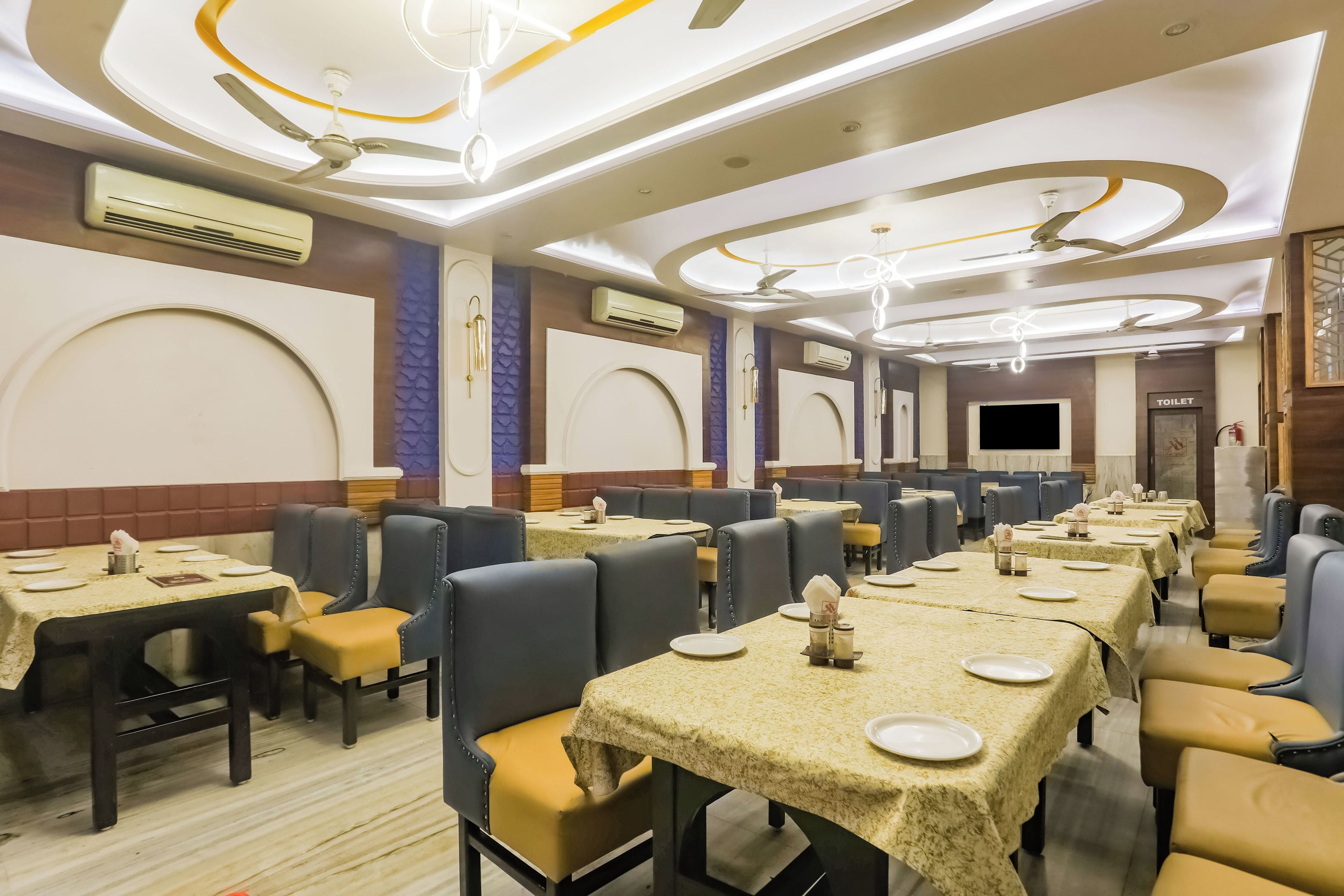 A restaurant with multiple tables and chairs, air conditioning units, and a ceiling fan.
