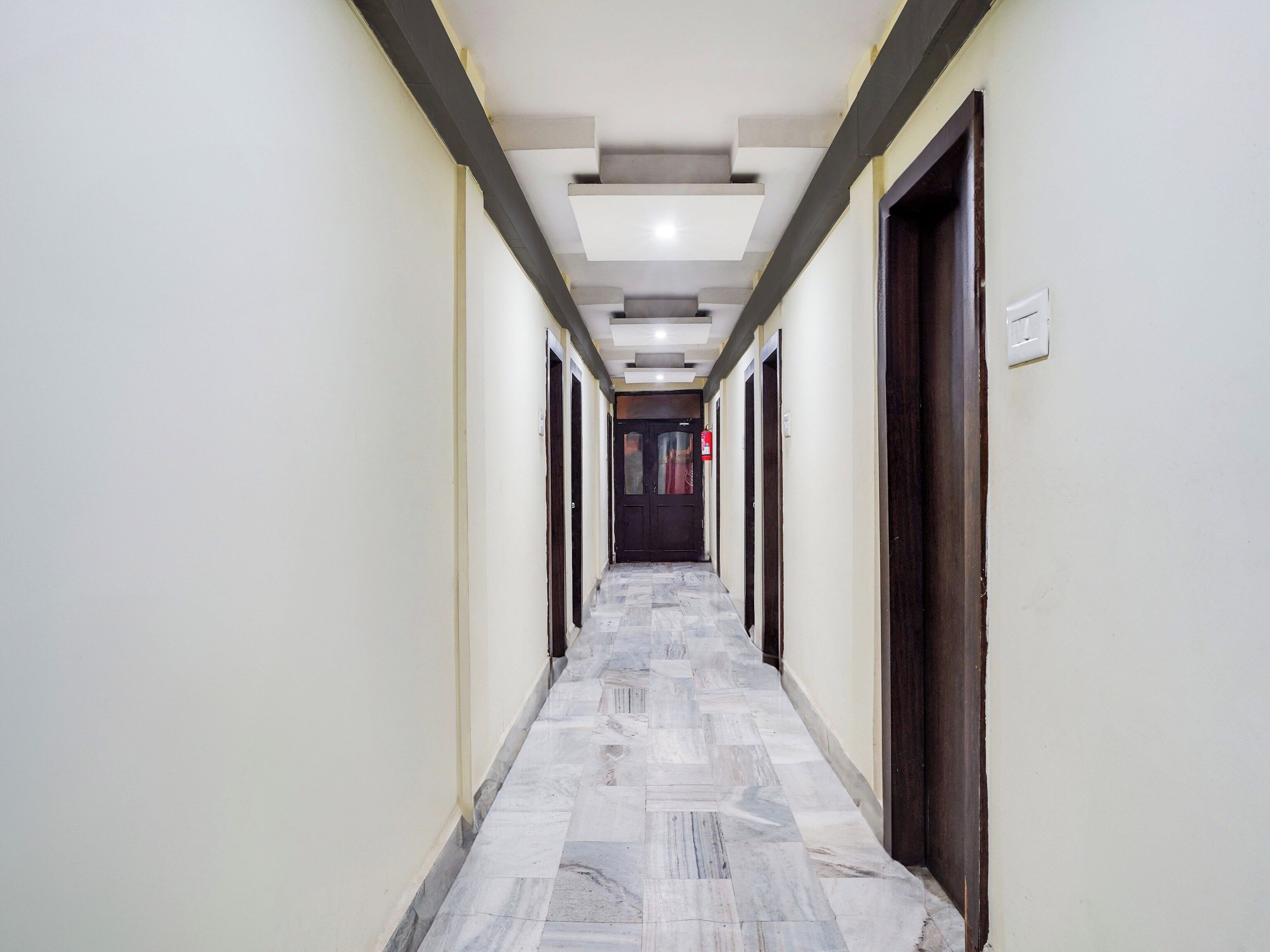 A long, narrow hallway with a tiled floor and doors on both sides.