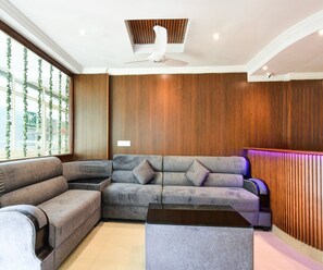 A modern living room with a sectional sofa, a coffee table, and a wooden accent wall. - Classic Vaishnavi Residency (Hyderabad)