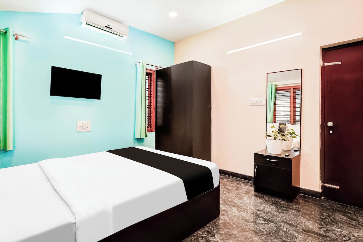 A hotel room with a bed, a wardrobe, a mirror, and a wall-mounted air conditioning unit.