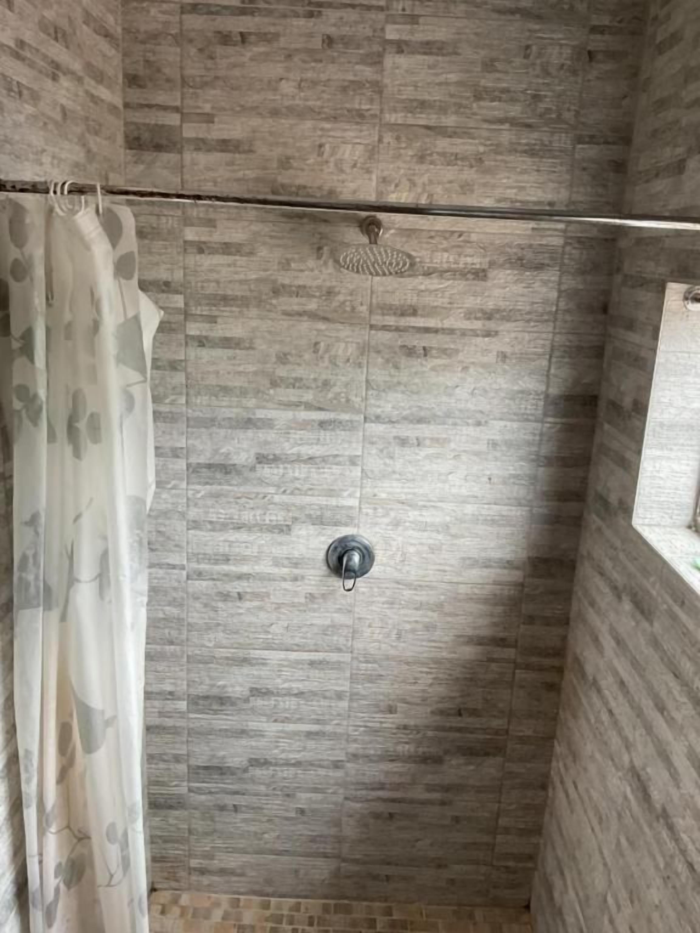 A shower area with a showerhead and a curtain.