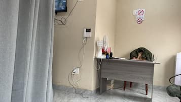 Una habitación con escritorio, silla, televisor montado en la pared y un cartel de 'No Fumar'.
