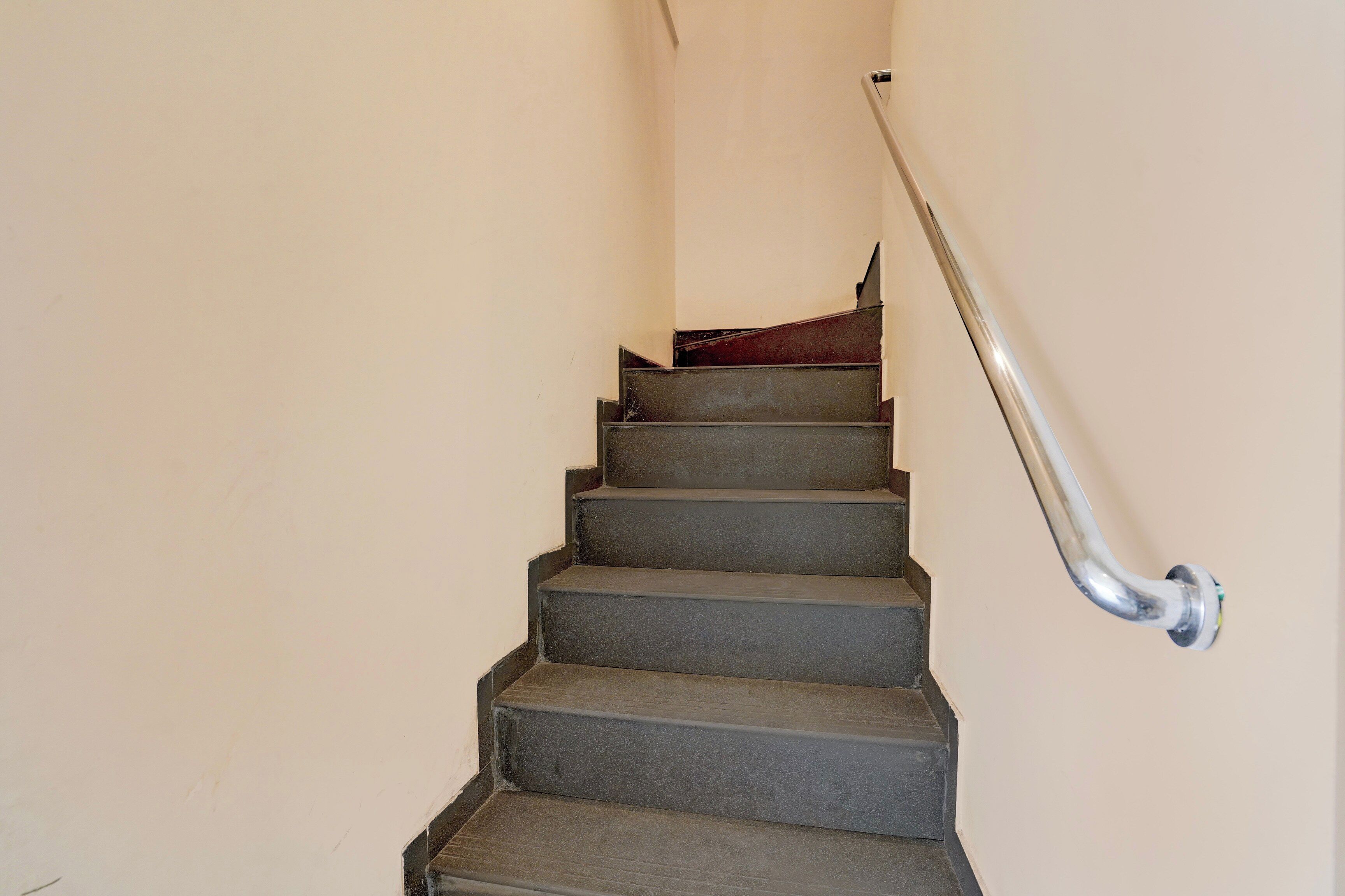 Una escalera con barandilla y alfombra roja.