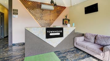 Un mostrador de recepción con un cartel que dice 'TOWNHOUSE Company Serviced' y un sofá a la derecha.