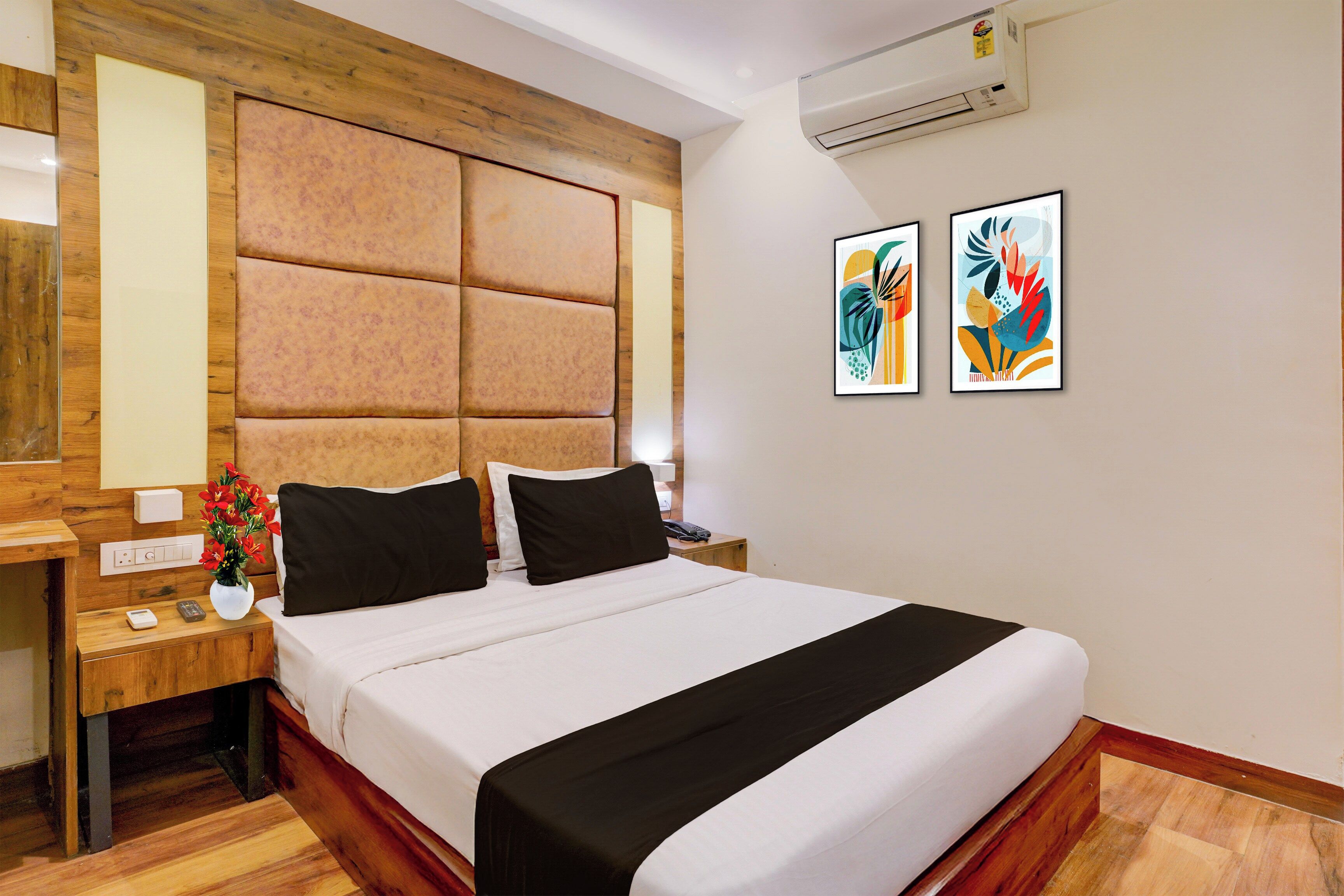 Una habitación de hotel con cama, mesita de noche y aire acondicionado instalado en la pared.