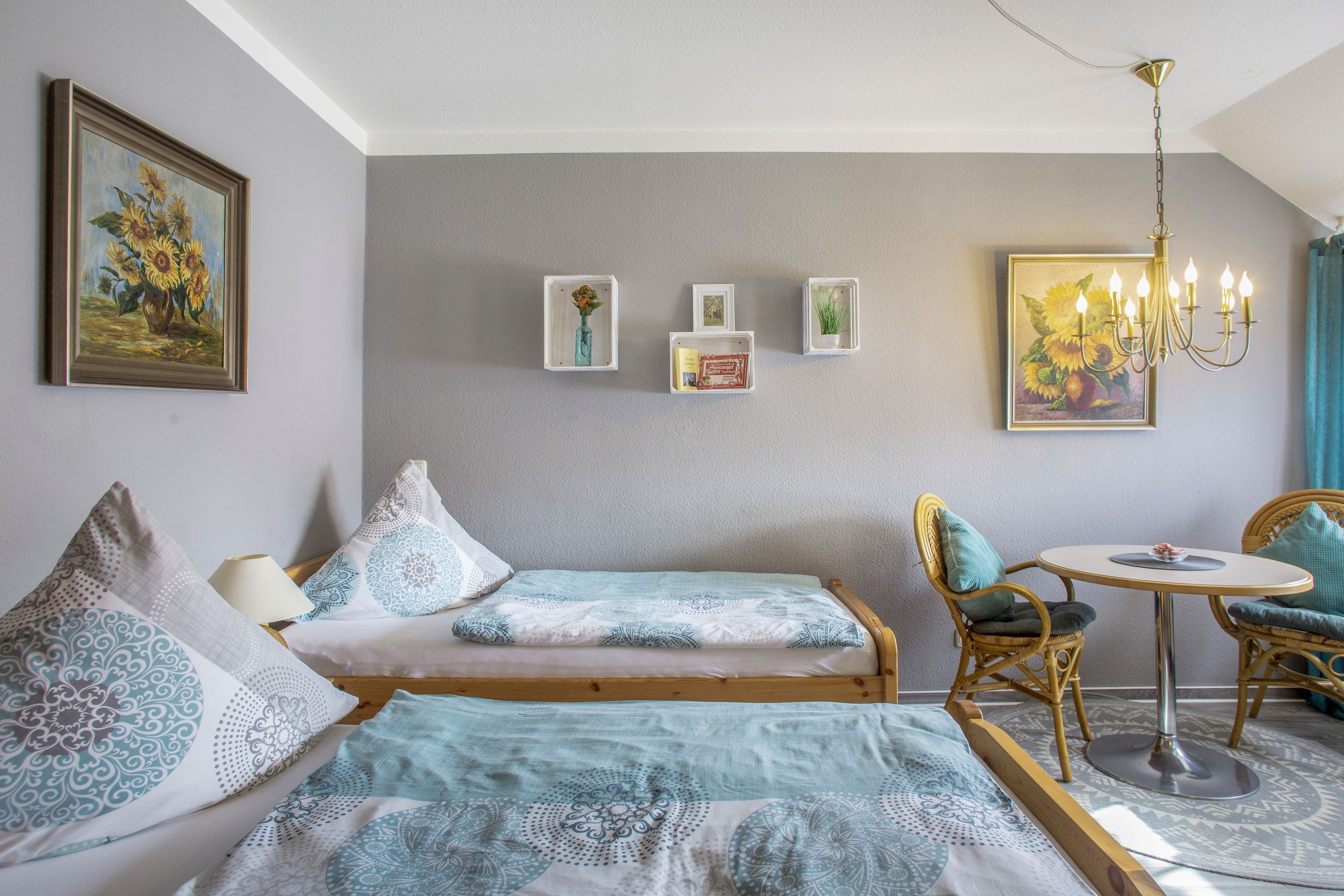 Une pièce comprenant un lit, une chaise, une table et un lustre.