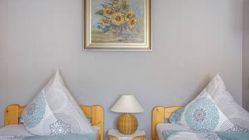 Ein Schlafzimmer mit zwei Betten, einem Nachttisch mit Lampe und einem gerahmten Gemälde an der Wand.
