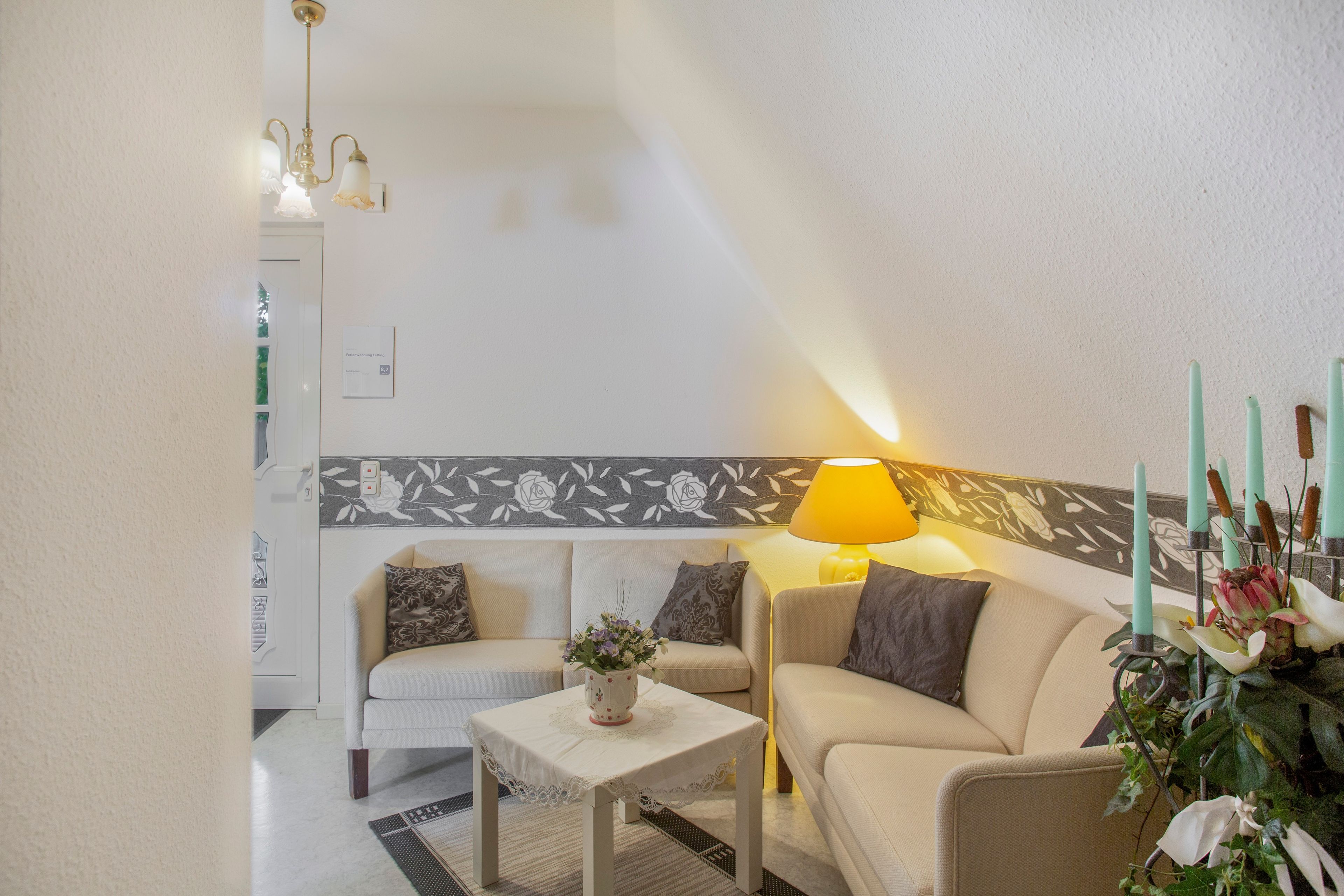A living room with a sofa, a small table, a lamp, and a decorative wall panel.