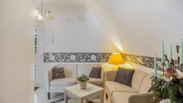 A living room with a sofa, a small table, a lamp, and a decorative wall panel.
