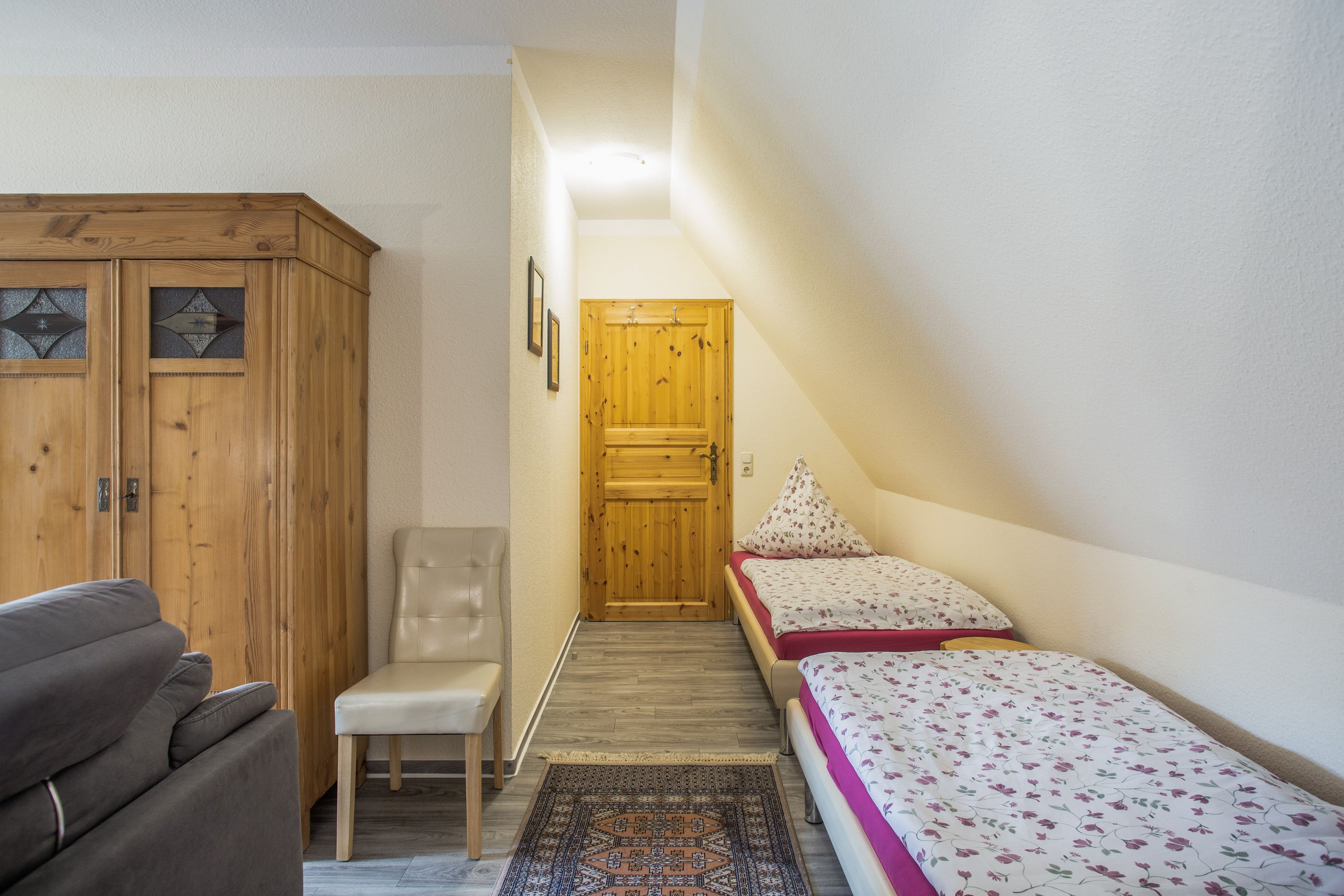 Une chambre  à coucher avec un lit, une chaise, une armoire et une porte.