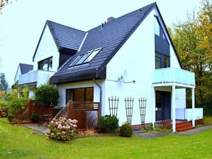 A two-story house with a sloped roof, a balcony, and a satellite dish. - Waldstrasse - Holiday Apartment 26 (Wyk auf Foehr)