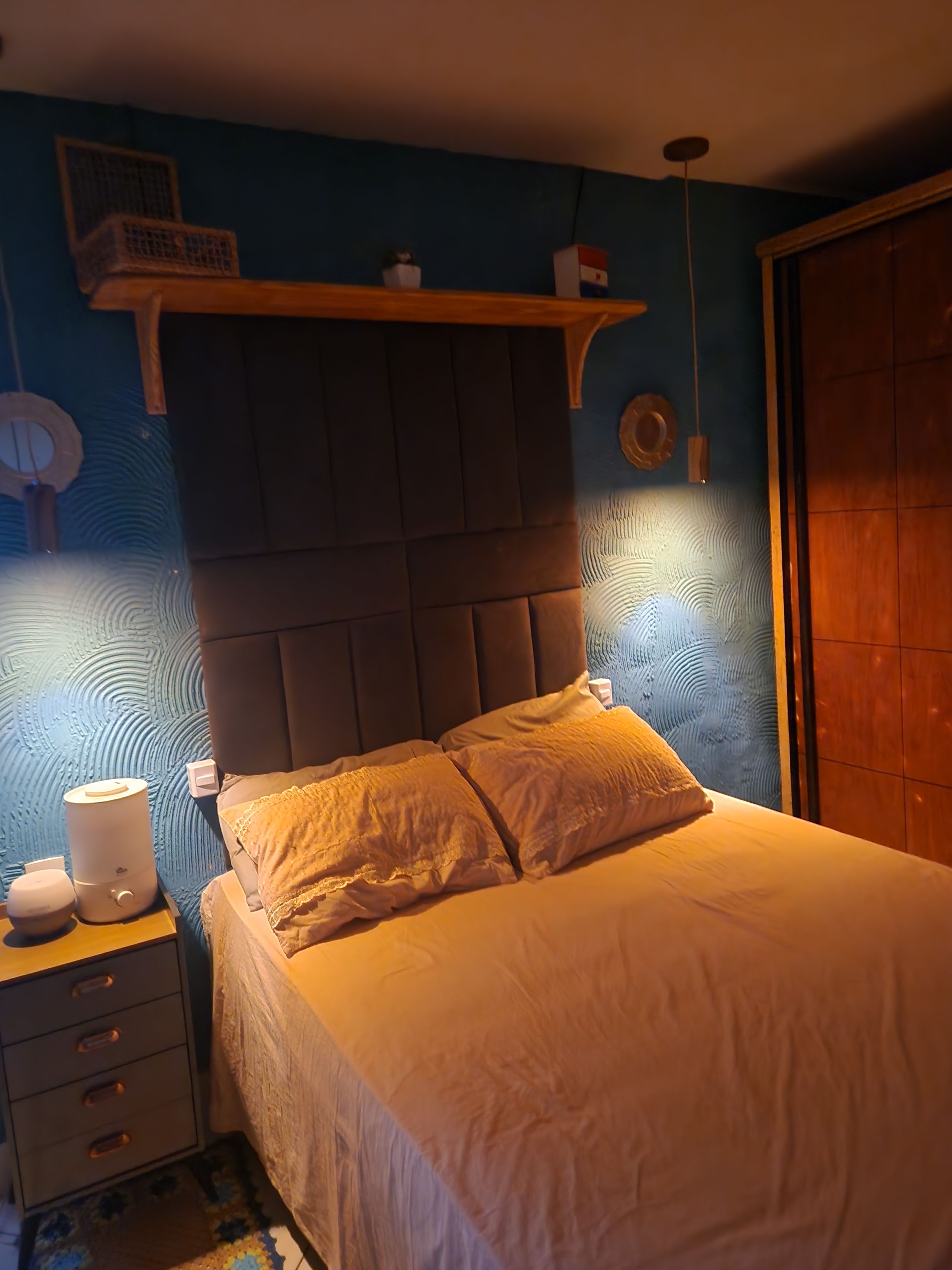 Un dormitorio con cama, mesita de noche y velador.